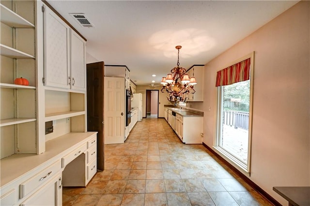 kitchen featuring white cabinetry, hanging light fixtures, built in desk, and a notable chandelier