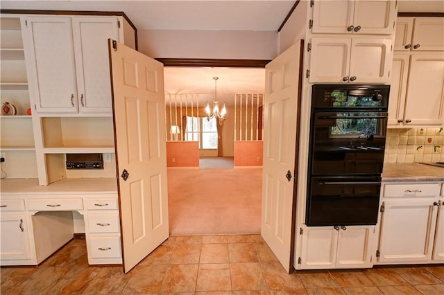 kitchen with white cabinetry, light carpet, double oven, a notable chandelier, and pendant lighting