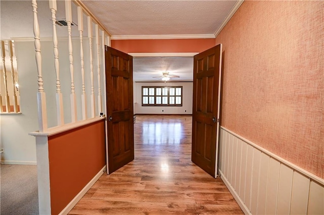 hall with a textured ceiling, light hardwood / wood-style flooring, and ornamental molding