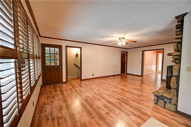 unfurnished living room with a fireplace, light hardwood / wood-style floors, ceiling fan, and crown molding