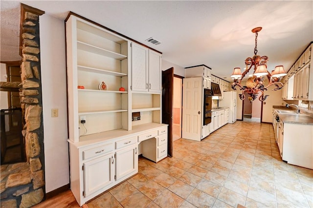 kitchen featuring a chandelier, hanging light fixtures, sink, and white cabinets