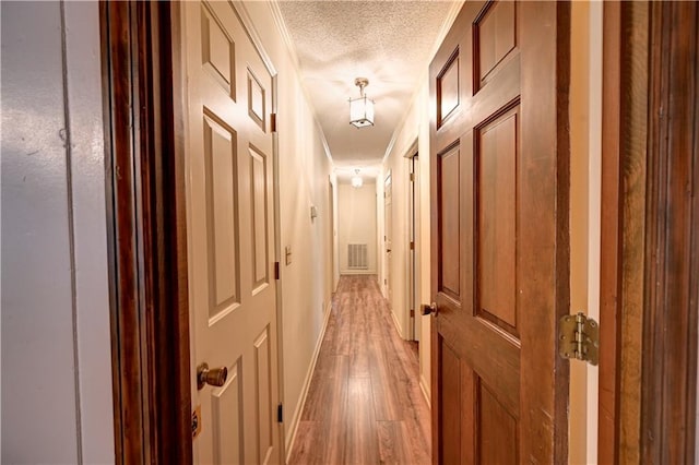 hall featuring a textured ceiling, crown molding, and light hardwood / wood-style flooring