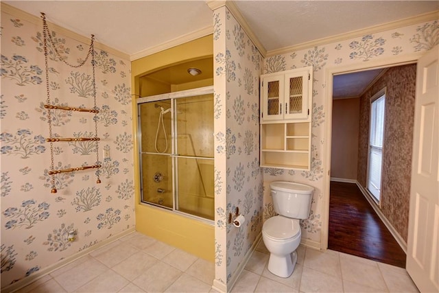 bathroom with hardwood / wood-style floors, combined bath / shower with glass door, toilet, and crown molding