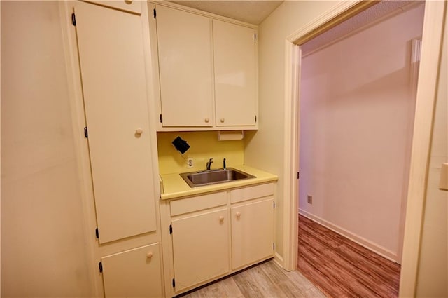 interior space featuring white cabinetry, light hardwood / wood-style floors, and sink