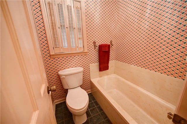 bathroom with tile walls, a bath, tile patterned floors, and toilet