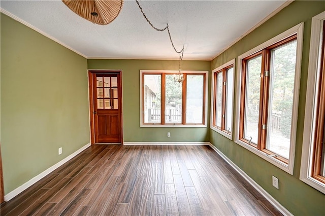 unfurnished dining area featuring a textured ceiling, a notable chandelier, dark hardwood / wood-style floors, and crown molding