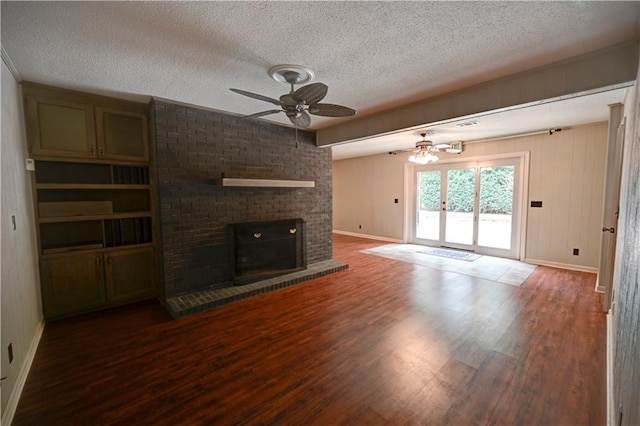 unfurnished living room featuring a textured ceiling, hardwood / wood-style floors, ceiling fan, and a fireplace