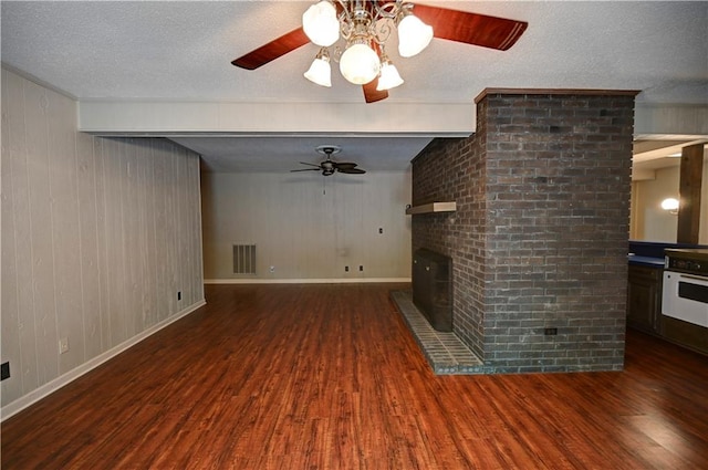 unfurnished living room with dark wood-type flooring, ceiling fan, a textured ceiling, and wood walls