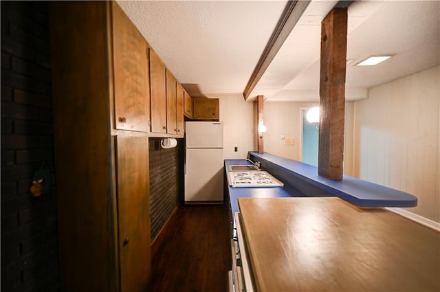 kitchen featuring dark hardwood / wood-style flooring, wood walls, white refrigerator, and sink