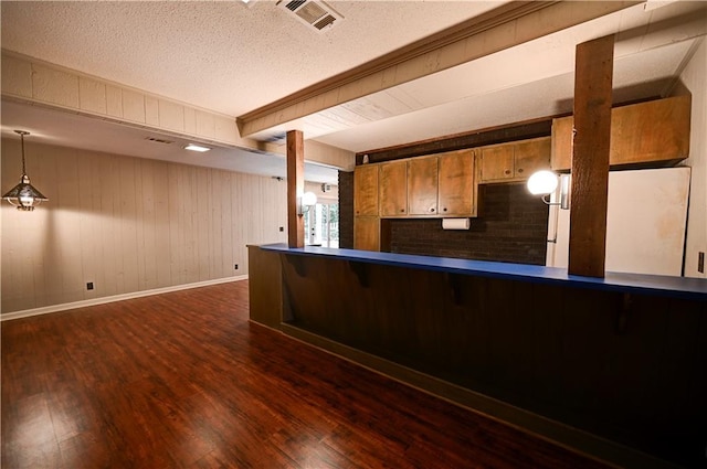 interior space featuring white refrigerator, kitchen peninsula, wood walls, dark hardwood / wood-style floors, and pendant lighting