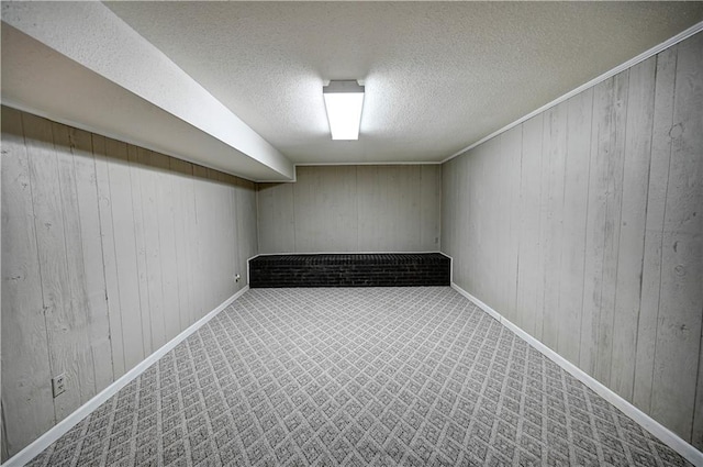 basement with wood walls, carpet floors, and a textured ceiling