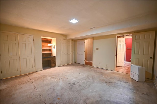 unfurnished bedroom featuring multiple closets and concrete floors