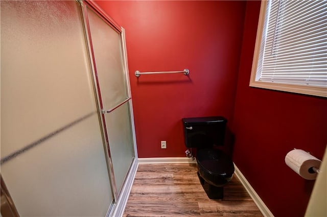 bathroom featuring wood-type flooring, toilet, and a shower with shower door