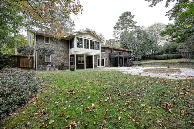 back of house with a sunroom, a lawn, and a deck