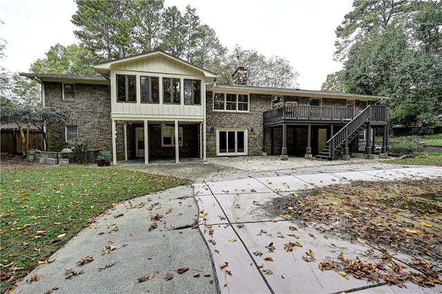 back of house with a deck, a lawn, a sunroom, and a patio area