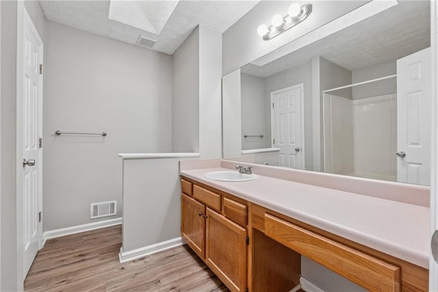 4200 Sterling Pointe Dr, Douglasville, GA 30135 - bathroom featuring wood finished floors, vanity, a shower, baseboards, and a textured ceiling