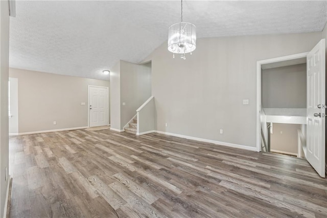 4200 Sterling Pointe Dr, Douglasville, GA 30135 - unfurnished living room featuring a textured ceiling, a chandelier, wood finished floors, stairs, and baseboards