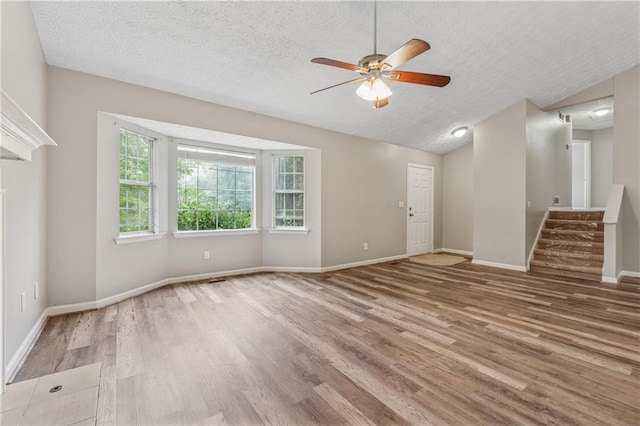 4200 Sterling Pointe Dr, Douglasville, GA 30135 - unfurnished living room featuring a ceiling fan, wood finished floors, a textured ceiling, baseboards, and lofted ceiling