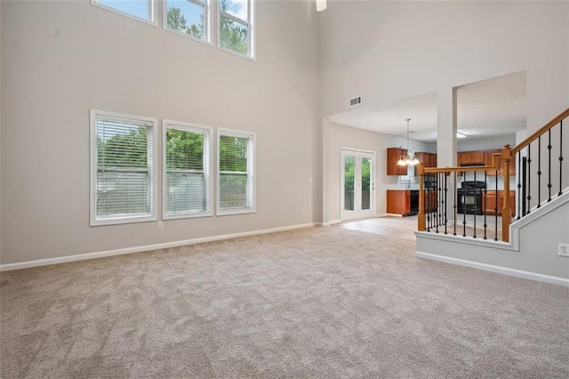 2040 Village Green Dr, Fairburn, GA 30213 - unfurnished living room featuring a chandelier, light colored carpet, a high ceiling, and stairway
