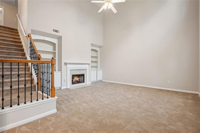 2040 Village Green Dr, Fairburn, GA 30213 - unfurnished living room featuring carpet flooring, a high ceiling, a ceiling fan, built in features, and stairway