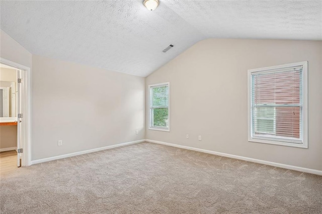 2040 Village Green Dr, Fairburn, GA 30213 - unfurnished bedroom with lofted ceiling, carpet floors, a textured ceiling, and ensuite bath