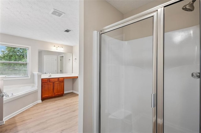 2040 Village Green Dr, Fairburn, GA 30213 - bathroom featuring wood finished floors, a textured ceiling, a shower stall, vanity, and a garden tub