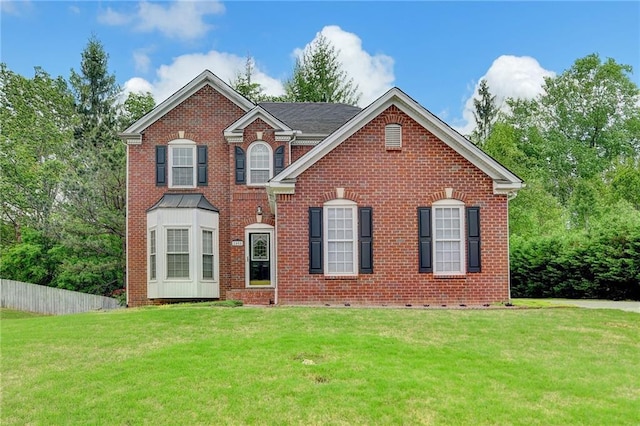 view of front facade with a front lawn, brick siding, and fence