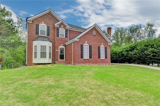 view of front of property with a chimney, brick siding, and a front yard