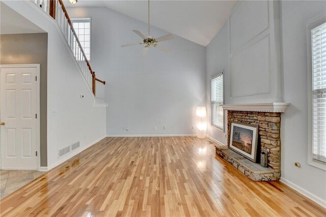 unfurnished living room featuring high vaulted ceiling, ceiling fan, a wealth of natural light, and light wood-style floors