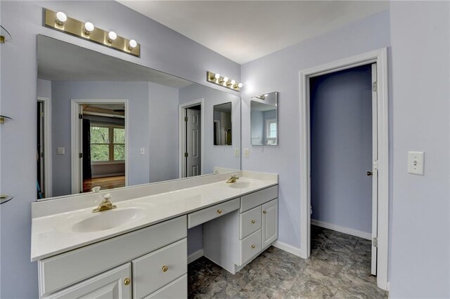 full bathroom with double vanity, baseboards, and a sink