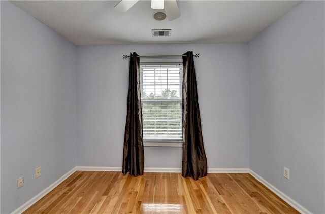 unfurnished room with baseboards, light wood-style flooring, visible vents, and ceiling fan