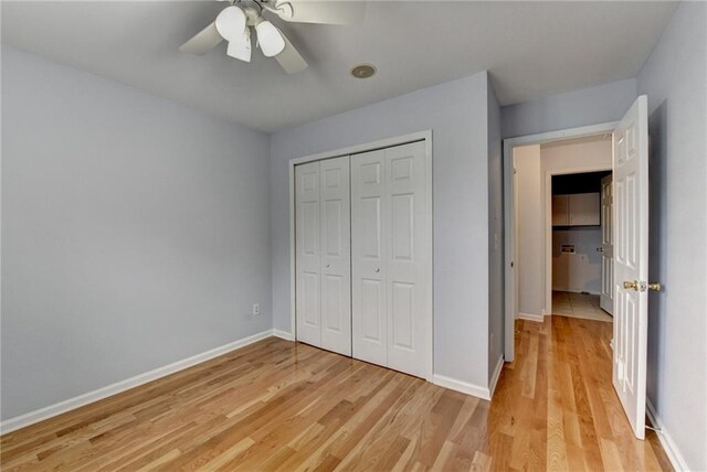 unfurnished bedroom with light wood-style floors, a closet, baseboards, and ceiling fan