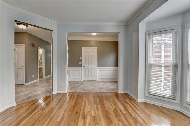 unfurnished room featuring baseboards, light wood-style floors, and crown molding