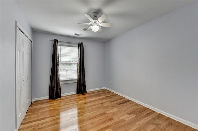 unfurnished bedroom featuring ceiling fan, baseboards, light wood-style floors, and a closet