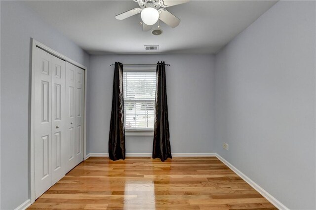 unfurnished bedroom featuring baseboards, visible vents, light wood-style floors, and a closet