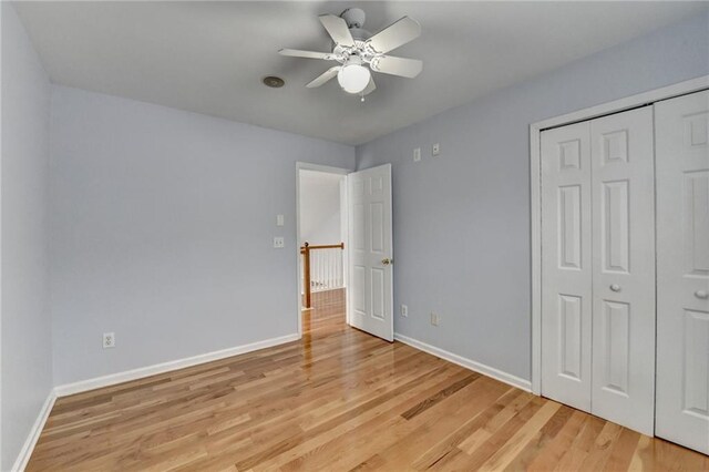 unfurnished bedroom featuring baseboards, a ceiling fan, light wood-style floors, and a closet