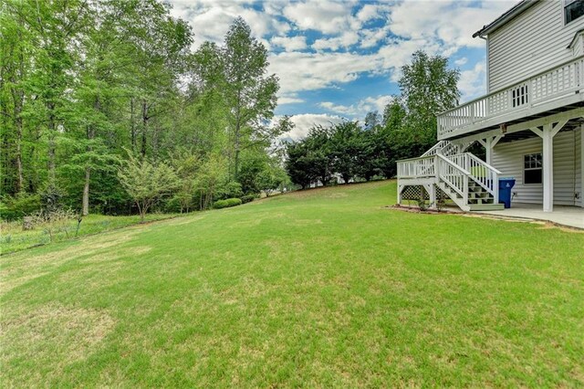 view of yard featuring stairway, a wooden deck, and a patio area