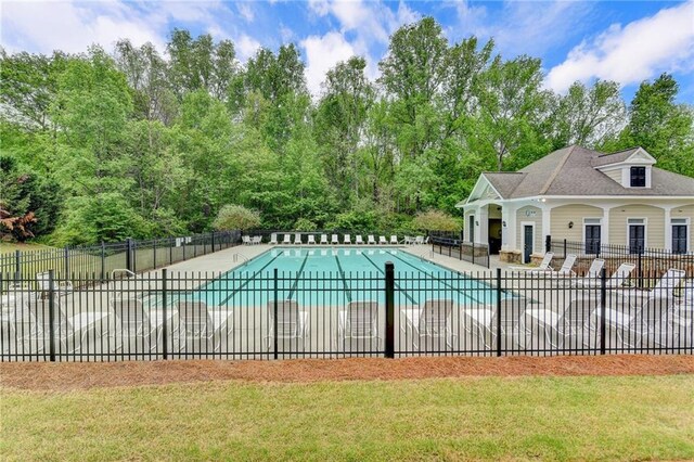 community pool featuring fence, a lawn, and a patio