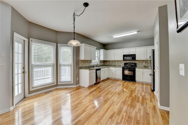 kitchen with black appliances, decorative backsplash, white cabinets, and light wood-style flooring