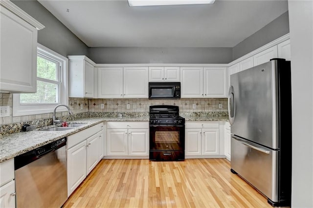 kitchen with backsplash, light wood-style floors, a sink, and black appliances