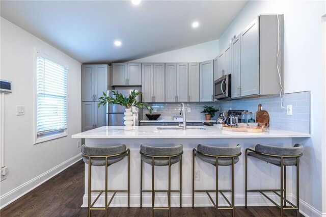 kitchen featuring a breakfast bar, sink, decorative backsplash, appliances with stainless steel finishes, and kitchen peninsula