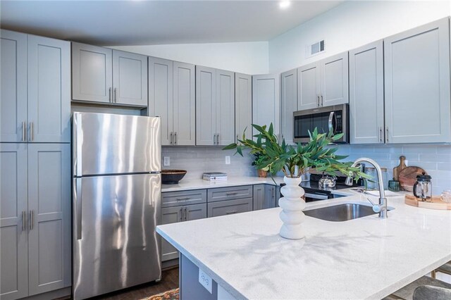 kitchen with sink, light stone countertops, appliances with stainless steel finishes, tasteful backsplash, and a kitchen bar