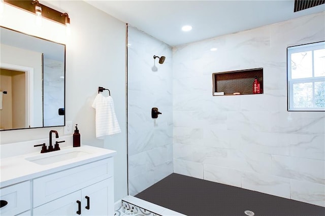 bathroom with vanity and a tile shower