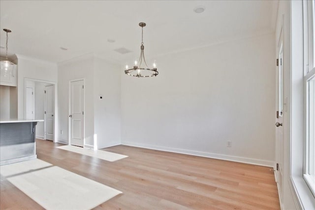 unfurnished dining area featuring baseboards, light wood-style floors, and a chandelier