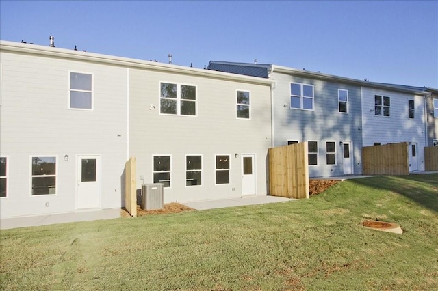 rear view of property with a lawn, cooling unit, and fence