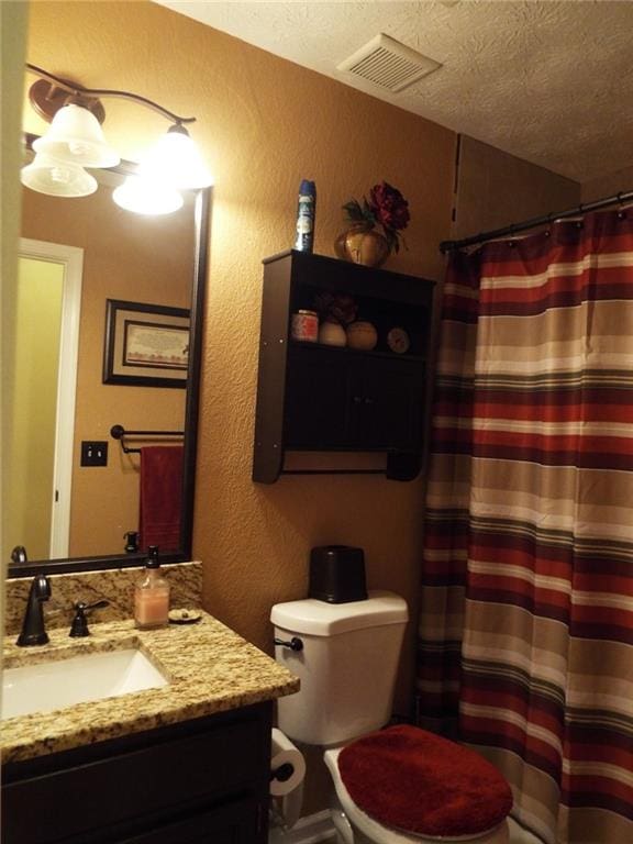 bathroom featuring vanity, a textured ceiling, and toilet