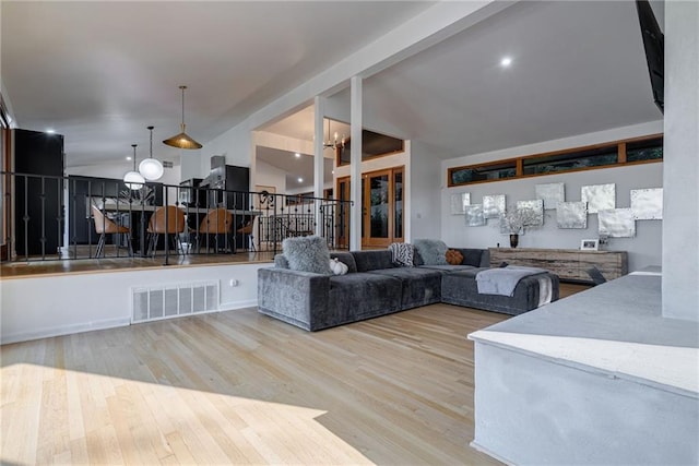 living room with vaulted ceiling with beams, light wood-type flooring, and an inviting chandelier