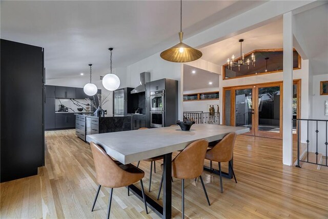 dining room featuring light hardwood / wood-style floors, vaulted ceiling, and a chandelier