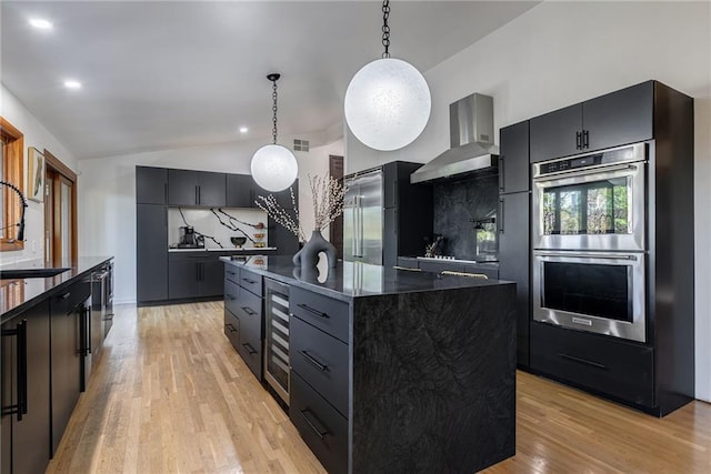 kitchen featuring decorative backsplash, wall chimney exhaust hood, stainless steel appliances, decorative light fixtures, and a kitchen island