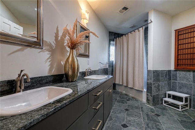 bathroom with shower / bath combo with shower curtain, vanity, and tile walls